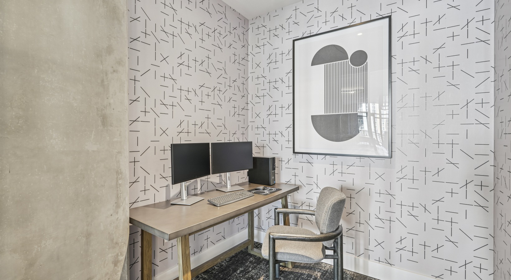 A coworking room with a green wall and individual black tables with chairs.