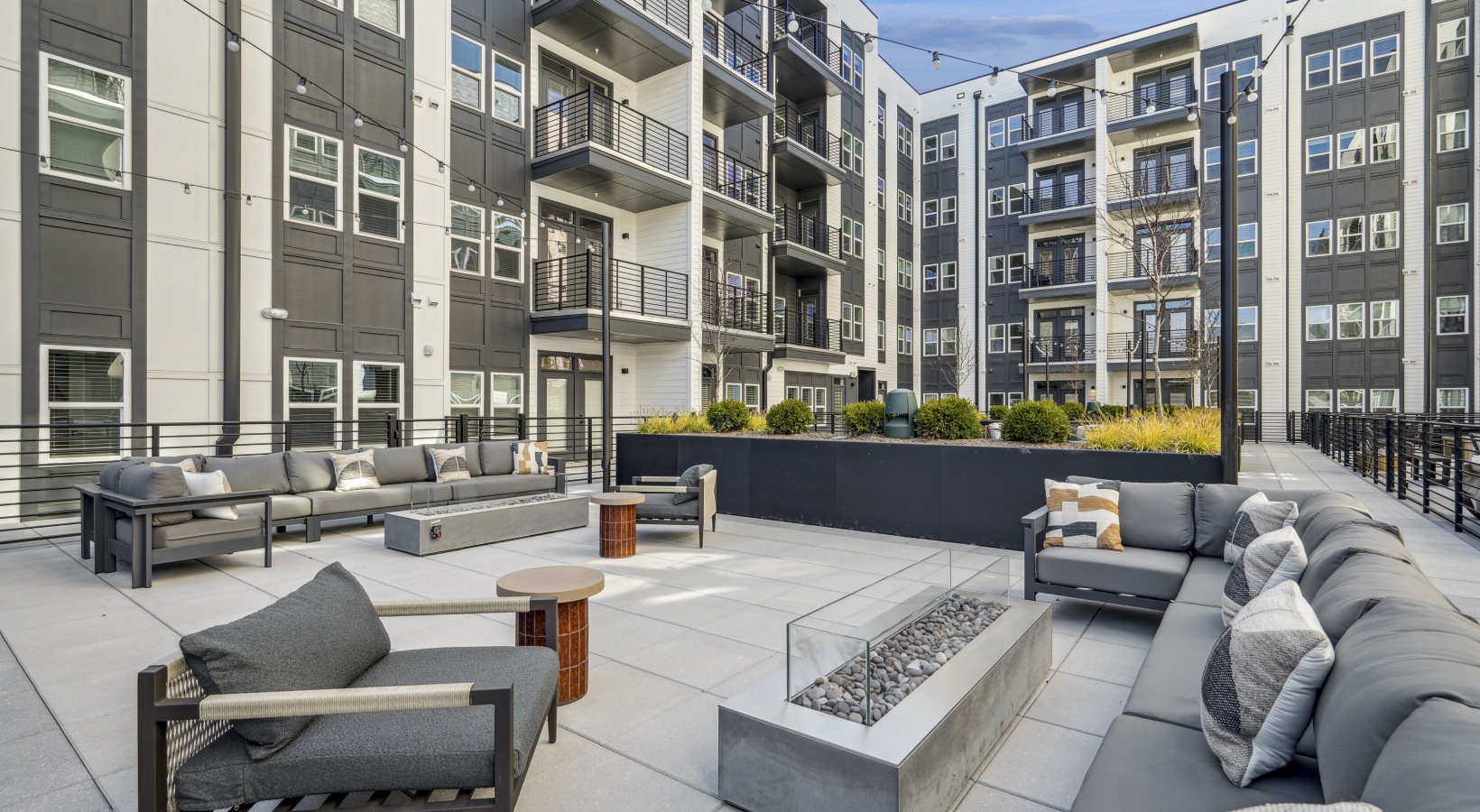 A large swimming pool is surrounded by a patio with chairs and umbrellas.